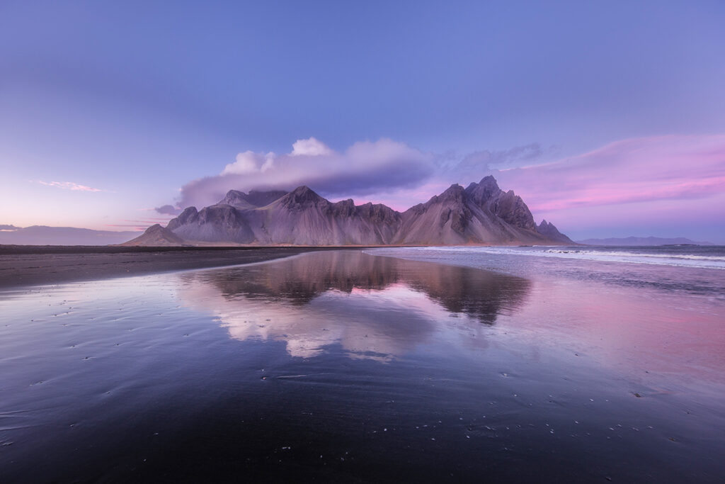 A large landscape of mountains in the distance reflecting off the ocean